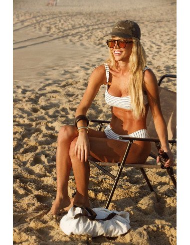 Modelo usando biquíni listrado texturizado branco e preto com top inteiro e calcinha borboleta na praia